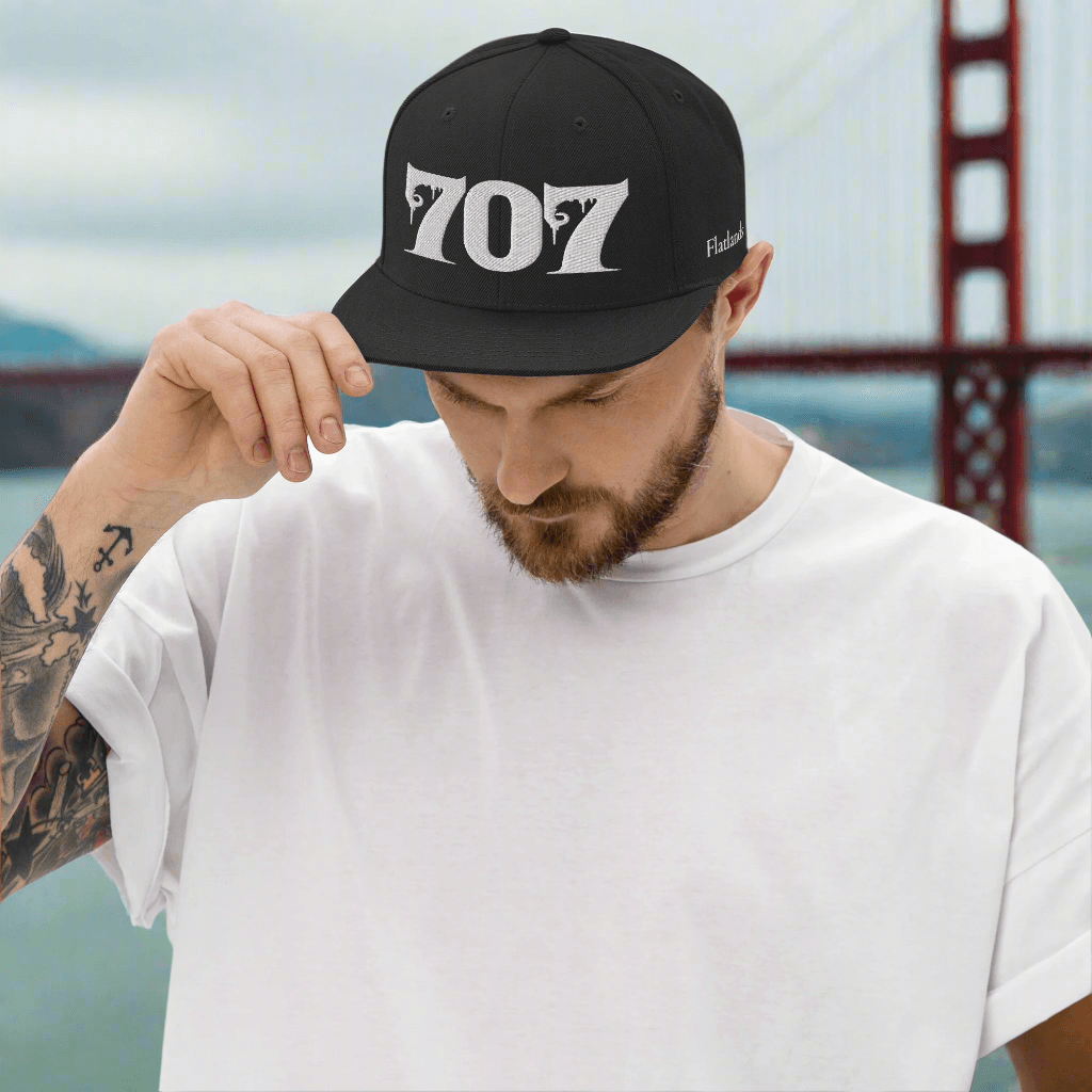 Man wearing Deadpan Couture 707 Classic Snapback Hat in black with white gothic-style '707' embroidery.