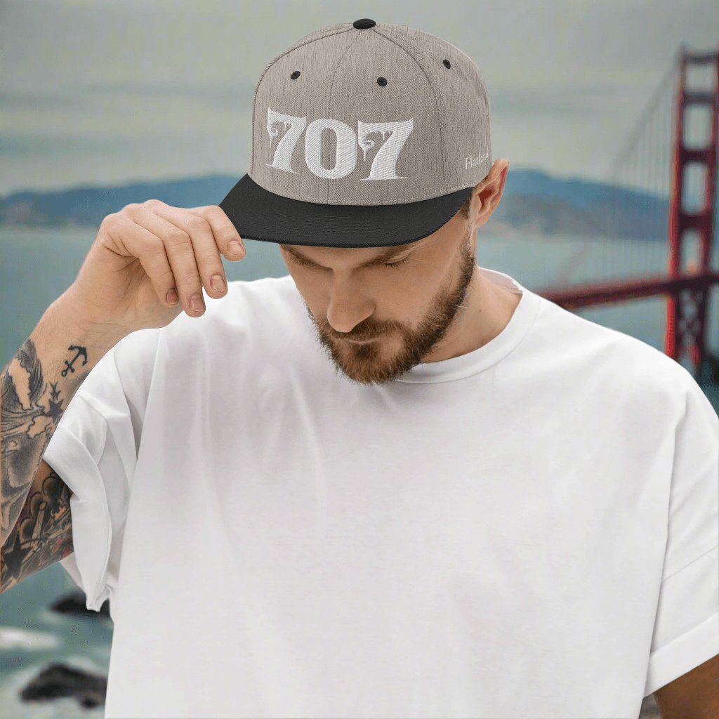 Man wearing Deadpan Couture 707 Classic Snapback Hat in black with white gothic-style '707' embroidery.