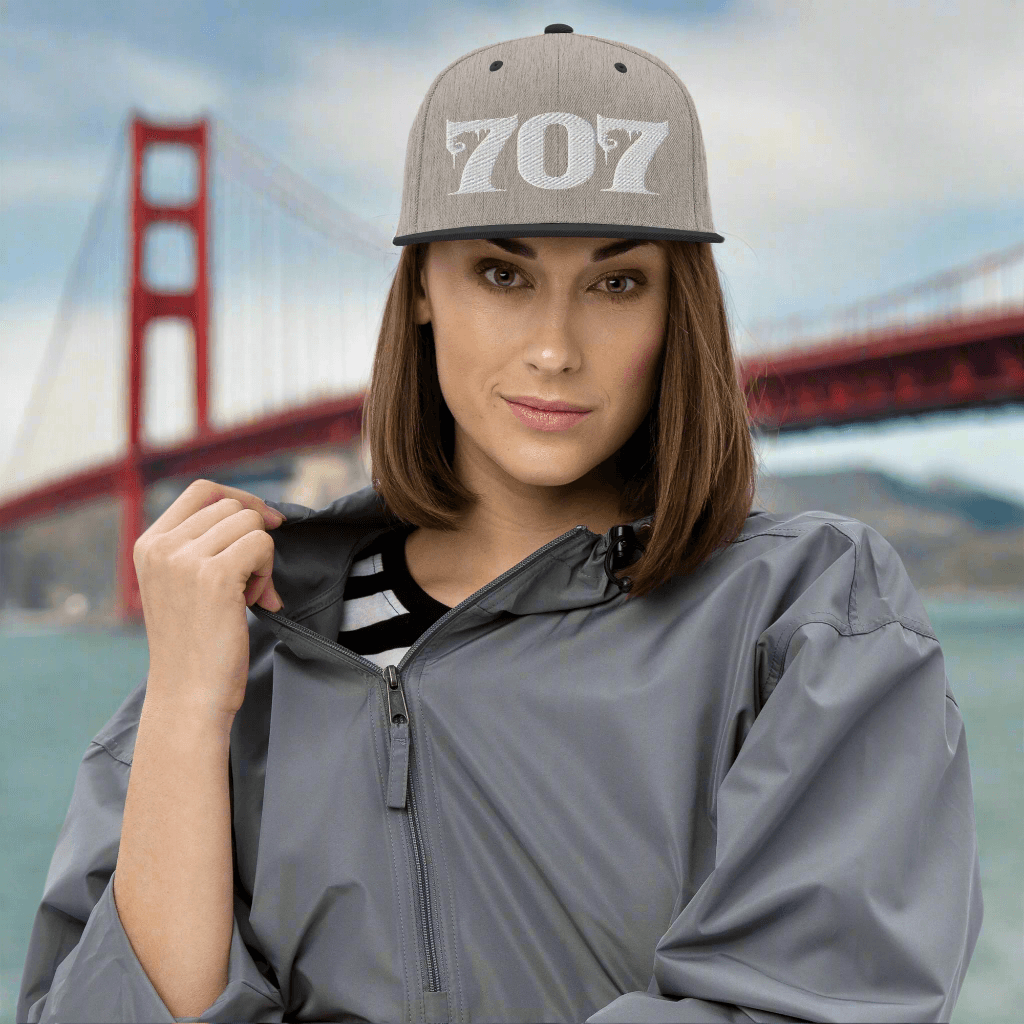 Woman wearing Deadpan Couture 707 Classic Snapback Hat in black with white gothic-style '707' embroidery.