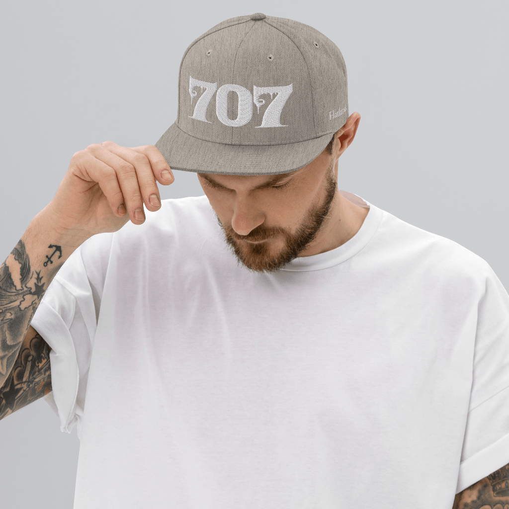 Man wearing Deadpan Couture 707 Classic Snapback Hat in black with white gothic-style '707' embroidery.