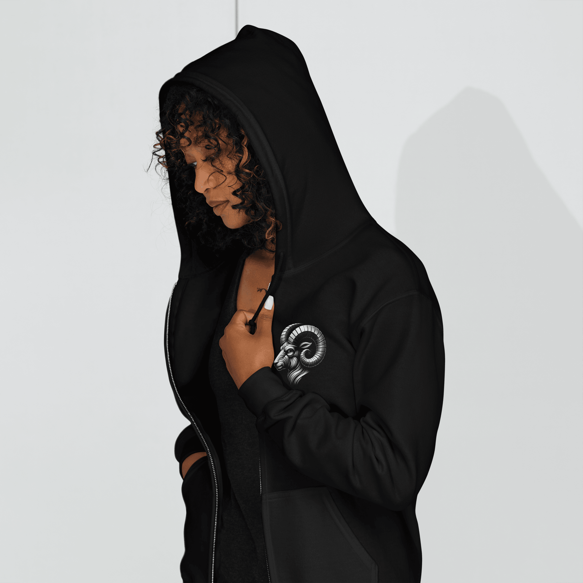 Black zip-up hoodie featuring a minimalist Aries ram graphic on the left chest, designed with intricate baroque elements, showcasing Deadpan Couture's edgy streetwear style.