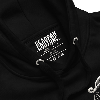 showing product details: A close-up view of the black Deadpan Couture hoodie, focusing on the inside label. The label displays the brand name, size (S), and fabric composition (65% cotton, 35% polyester). The image also includes a partial view of the ornate Libra scales design on the left chest, emphasizing the hoodie’s quality and attention to detail.