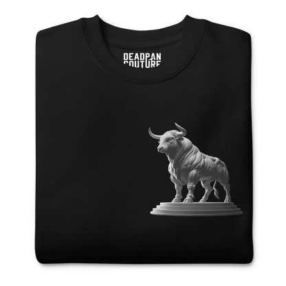 A neatly folded black Deadpan Couture sweatshirt with the Taurus bull statue design visible on the front left chest area. The illustration is clean and prominent against the black fabric.