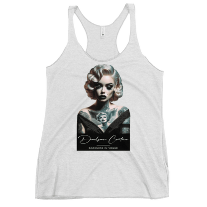 "White women's racerback tank top with a graphic of a tattooed woman with vintage-style hair and makeup, accompanied by the text 'Deadpan Couture' and 'Darkness in Vogue' at the bottom."